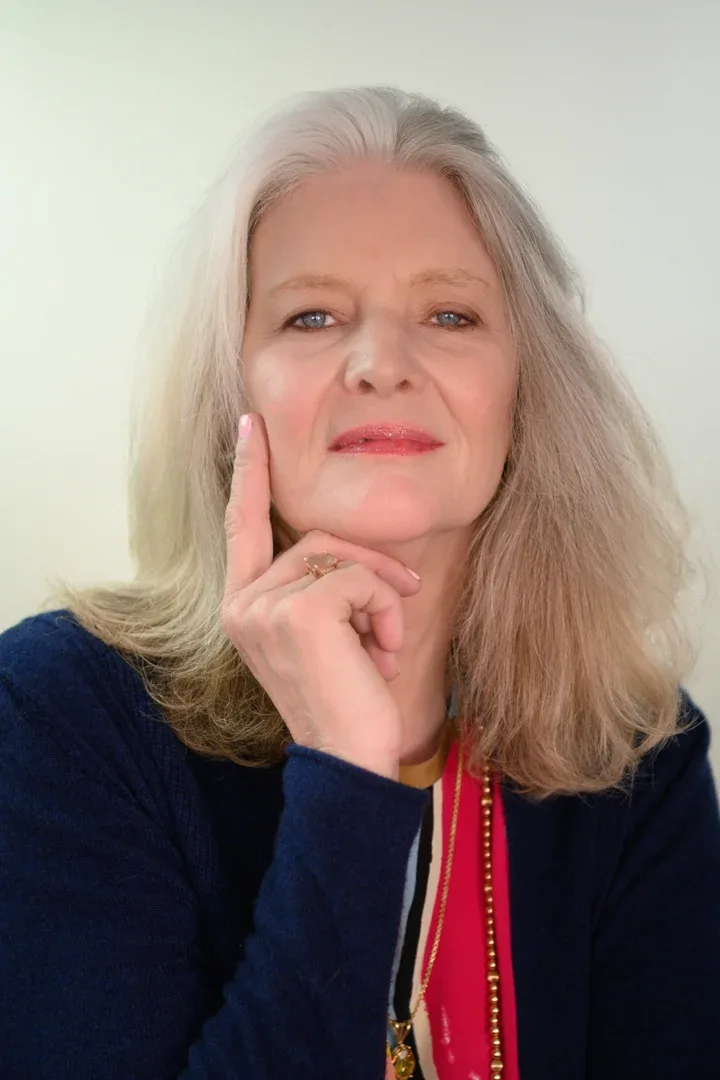 Patricia A. Tracy in a candid moment, smiling slightly with her hand under her chin, showcasing her patterned outfit and jewelry.