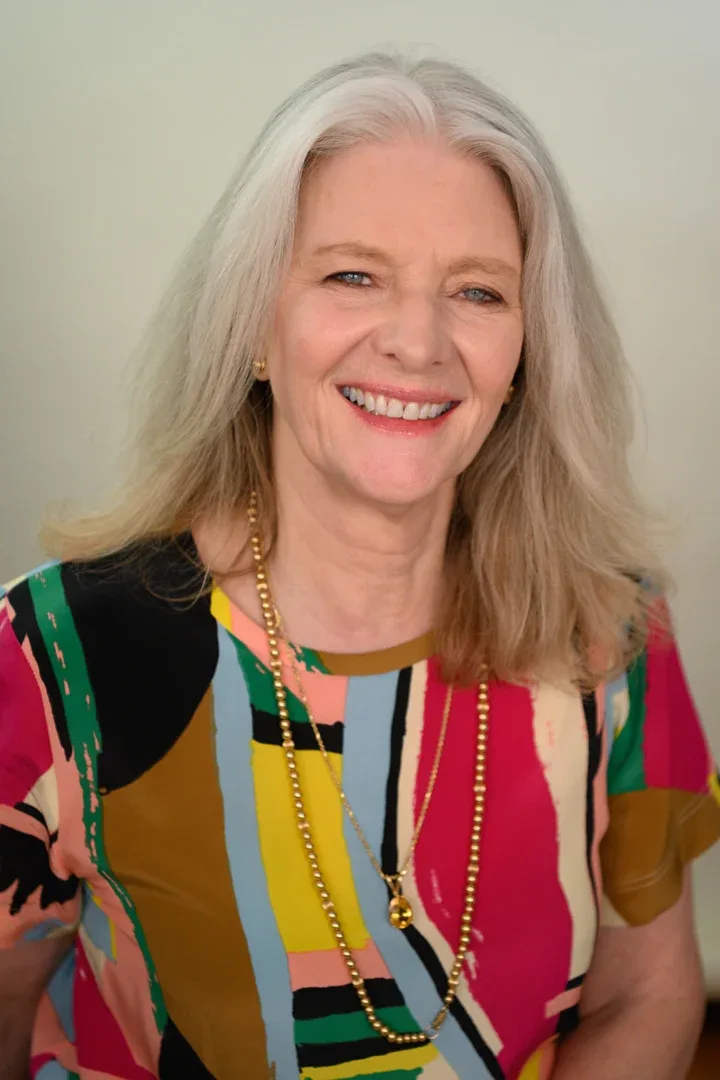Patricia A. Tracy reclining with a wide smile in a colorful dress.